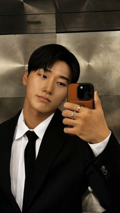 a man in a suit taking a selfie with his cell phone