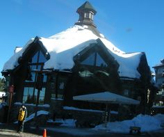 a building with snow on the roof and some people standing outside in front of it