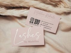 two business cards sitting on top of a bed next to a furnishing material