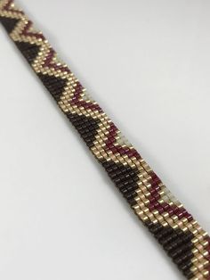 a close up of a bracelet on a white surface with red, black and gold beads