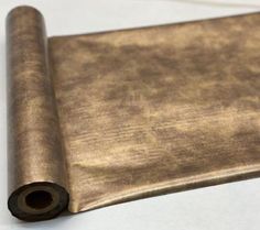 a roll of metallic foil sitting on top of a white tablecloth covered in brown paper