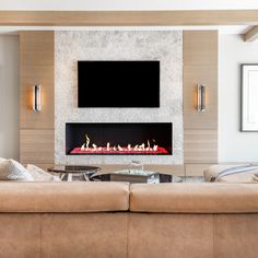 a living room with couches and a fire place in the wall above it is a flat screen tv