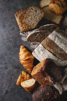 various types of breads and pastries on a black table top with paper towels