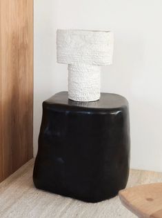 a black stool with a white toilet paper roll on top