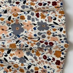 the fabric has flowers on it and is white with brown, blue, orange and red colors