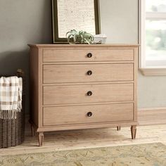 a wooden dresser sitting in a living room next to a basket and framed photograph on the wall