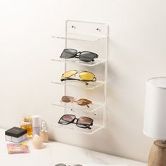 a pair of sunglasses hanging on the wall next to a lamp and other items in front of it