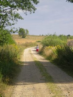 a person walking down a dirt road in the country