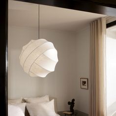 a bed room with a neatly made bed and a large light hanging from the ceiling