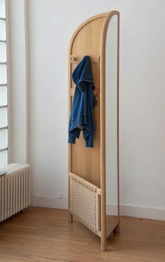 a wooden coat rack with blue clothes hanging on it's sides and a radiator in the background