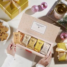 a person is holding an open gift box next to some cookies and crackers on a table