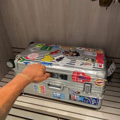 a person pointing at a suitcase with stickers on it