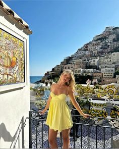 a woman standing on top of a balcony next to the ocean