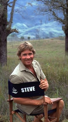 a man is sitting in a chair with a steve sign on his arm and smiling at the camera