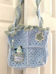 a crocheted purse hanging on the front door with a stuffed animal in it