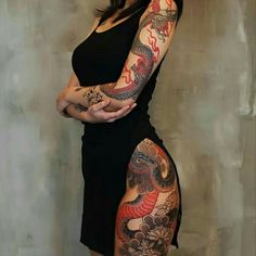 a woman with dragon tattoos on her arm and leg, standing in front of a wall