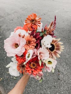 a person holding a bouquet of flowers in their hand on the street with no one around