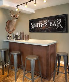 a bar with three stools and a deer head mounted on the wall above it