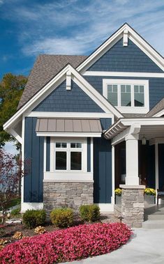 a house with blue siding and white trim on the windows, front door and porch