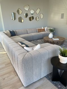 a living room filled with furniture and mirrors on the wall above it's coffee table