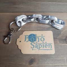 a metal chain with a tag attached to it sitting on a wooden table next to a pair of scissors