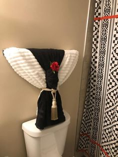 a white toilet sitting next to a black and white shower curtain with a red rose on it