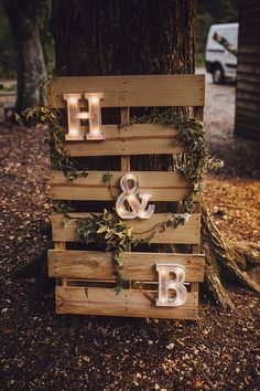 a wooden sign with lights on it that says h and b next to a tree