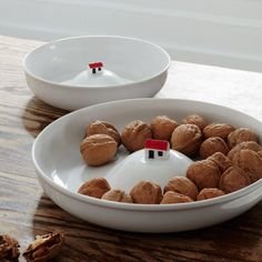 two bowls filled with nuts on top of a wooden table