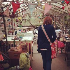 a woman and child are walking through a greenhouse with many tables and chairs in the background