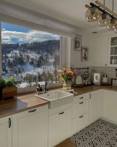 a kitchen with a large window looking out at the snow covered mountains outside it and flowers in vases on the counter