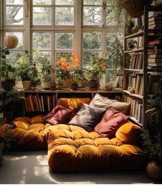 a living room filled with lots of plants and bookshelves next to a window