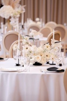 the table is set with white flowers and black place settings for an elegant wedding reception