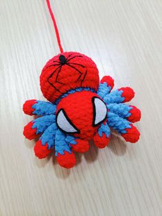 an ornament shaped like a spider man hanging from a string on a table