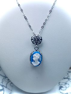 Simulated Blue & White Portrait Cameo Sterling Silver Pendant NecklaceEdward Design#P70 Introducing the Edward Design P70 Blue Cameo Portrait Pendant! This exquisite pendant is sure to make a lasting impression with its timeless, romantic design. Crafted from sterling silver and encrusted with a captivating 14mm by 10mm simulated Blue Cameo, you won't be able to resist the vintage Victorian style created by this remarkable piece of jewelry.The filigree detailing of the pendant and its bail adds Blue Cameo Necklace For Formal Occasions, Blue Cameo Jewelry For Formal Occasions, Formal Blue Cameo Jewelry, Edwardian Necklace, Filigree Necklaces, White Portrait, Romantic Design, Cameo Pendant, Sterling Silver Filigree