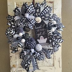 a black and white halloween wreath hanging on a door