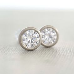 4 mm moissanite stud earrings, bezel set in 14k yellow, rose or white gold, or sterling silver. 14k white gold is pictured except for 6th photo which shows sterling silver. These earrings are made to order and will ship within 3-5 days. DETAILS - 4 mm moissanite - bezel setting - satin finish - solid 14k gold or sterling silver - white gold contains nickel, not rhodium plated - sold sterling silver or 14k gold backs - made to order within 3-5 days What is Moissanite? Moissanite is lab created si 14k White Gold Jewelry With Bezel Setting, Anniversary Diamond Earrings With Tension Setting, Classic Everyday Jewelry With Tension Setting, Modern Round Diamond Earrings As Gift, Modern White Gold Earrings With Bezel Setting, Minimalist Bezel Set Diamond Earrings For Formal Occasions, Anniversary Sterling Silver Earrings With Single Diamond, Sterling Silver Round Diamond Earrings With Tension Setting, Minimalist Diamond Earrings With Bezel Setting For Formal Occasions