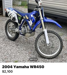 a blue dirt bike parked in front of a trailer with the words yamaha on it