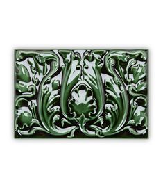 a green and white tile with an ornate design on the bottom, in front of a white background