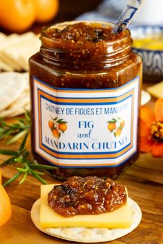 a jar of marmalade sitting on top of a wooden table next to crackers