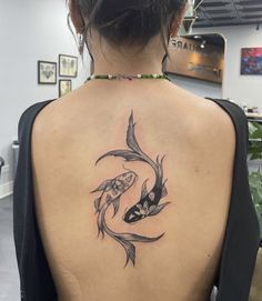 a woman with a tattoo on her back is looking at the fish in the water