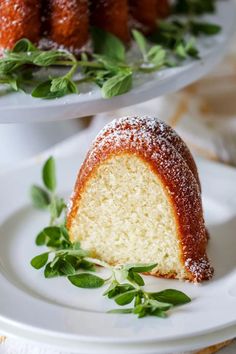 two plates topped with cakes covered in powdered sugar and sprinkled with green leaves