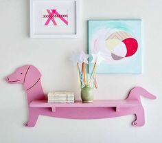 a pink shelf with some art on it