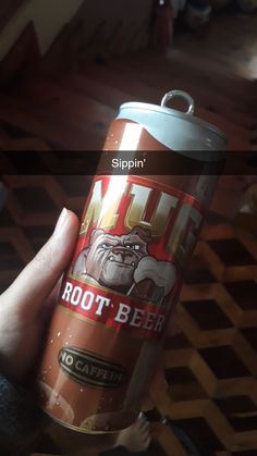 a person holding up a can of root beer