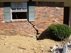 a brick house with green shutters on the windows and steps leading up to it