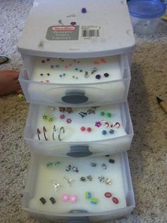 three plastic containers filled with different types of jewelry on top of a carpeted floor