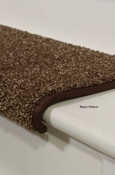 a close up view of the edge of a rug on a white surface with brown trim