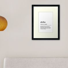 an aloha framed print hangs on the wall next to a couch and lamp