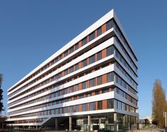 an office building with many windows and cars parked in the parking lot next to it