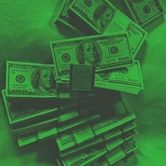 a pile of money sitting on top of a bed covered in green light next to each other