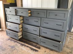 an old dresser is painted gray and has drawers on the bottom shelf with gold pulls